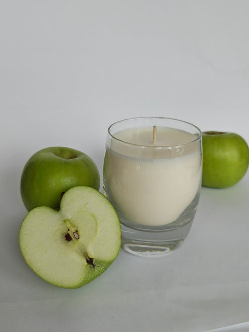 Candle in a glass jar with green apples on a white background