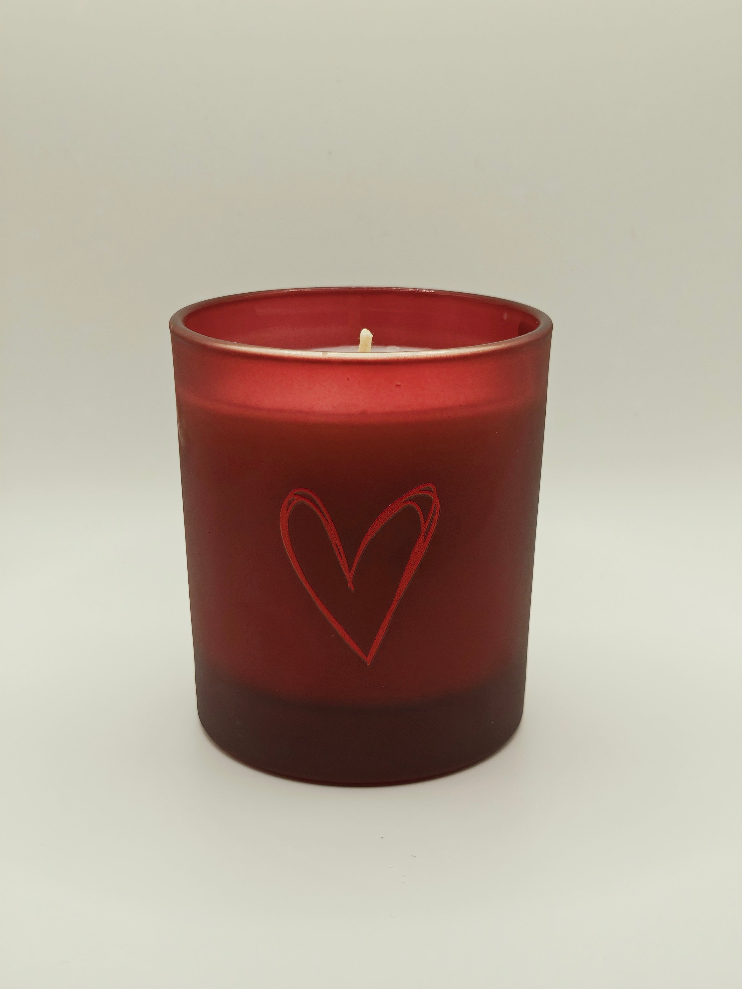 Red candle with a heart design on a white background