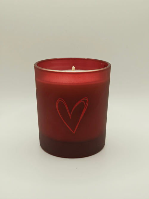 Red candle with a heart design on a white background