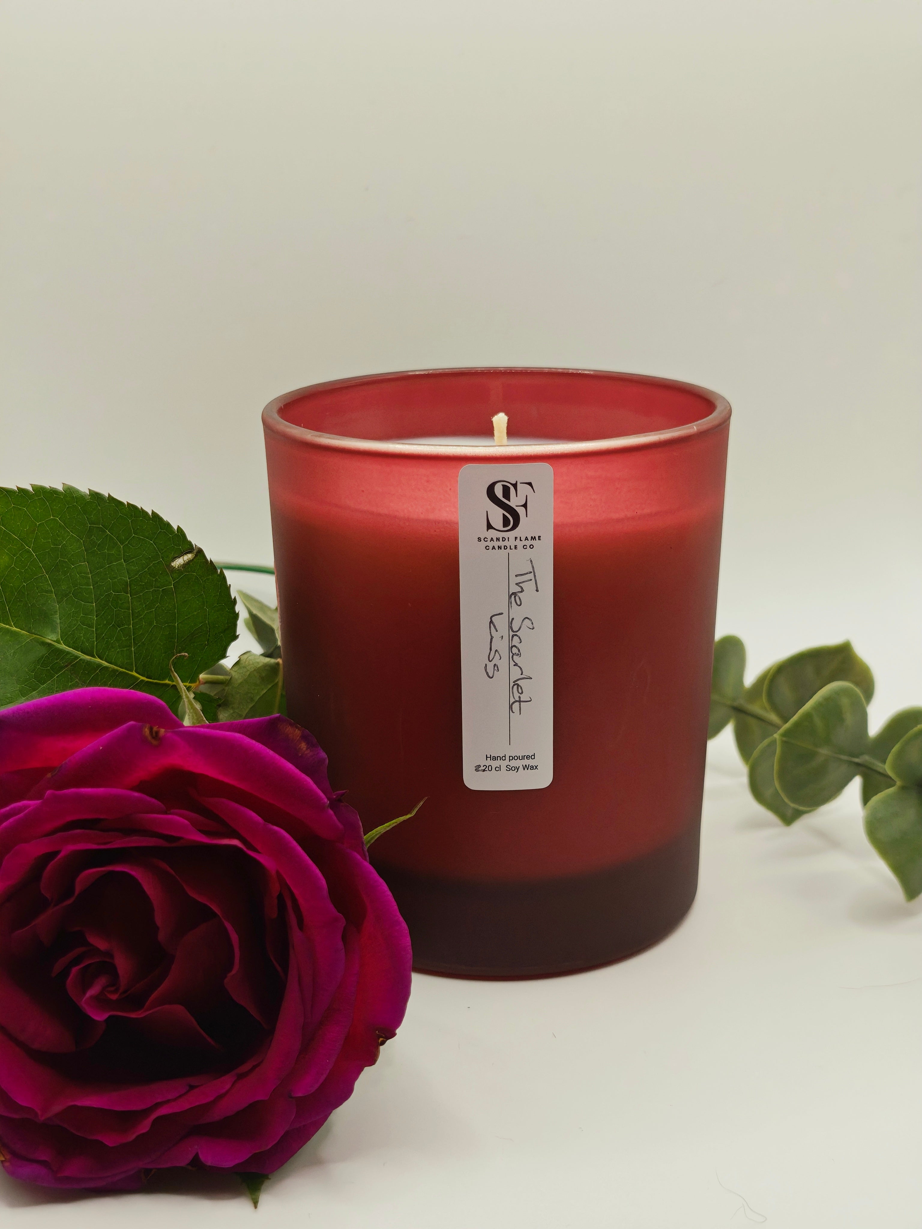 Red candle with a label 'The Scarlet Kiss' and a red rose on a light background